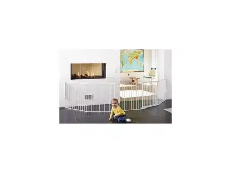 Baby Dan Flex XXL baba biztonsági rács. A Kandalló előtt van felállítva fehér színben. Falhoz van rögzítve csavarokkal mind a két vége. Középen egy ajtó található a babarácson, amit csak felnőtt tud kinyitni, így megakadályozza, hogy a gyermek megégesse magát a kandalóval.